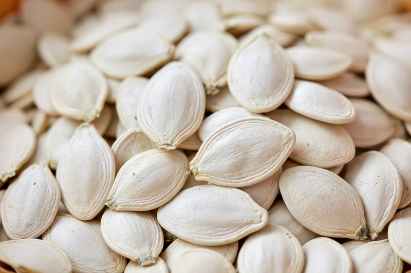 Closeup of raw white pumpkin seeds piled together filling the frame