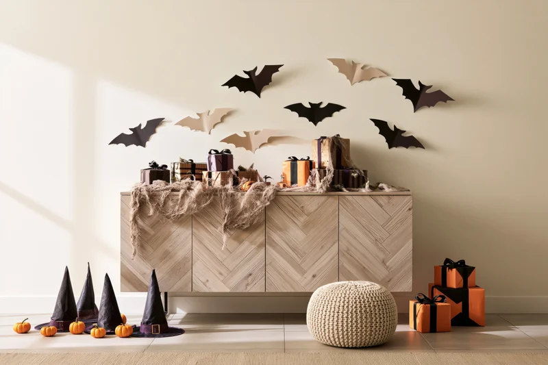 Halloween decorations on a wooden cabinet with gifts and witch hats in a living room corner