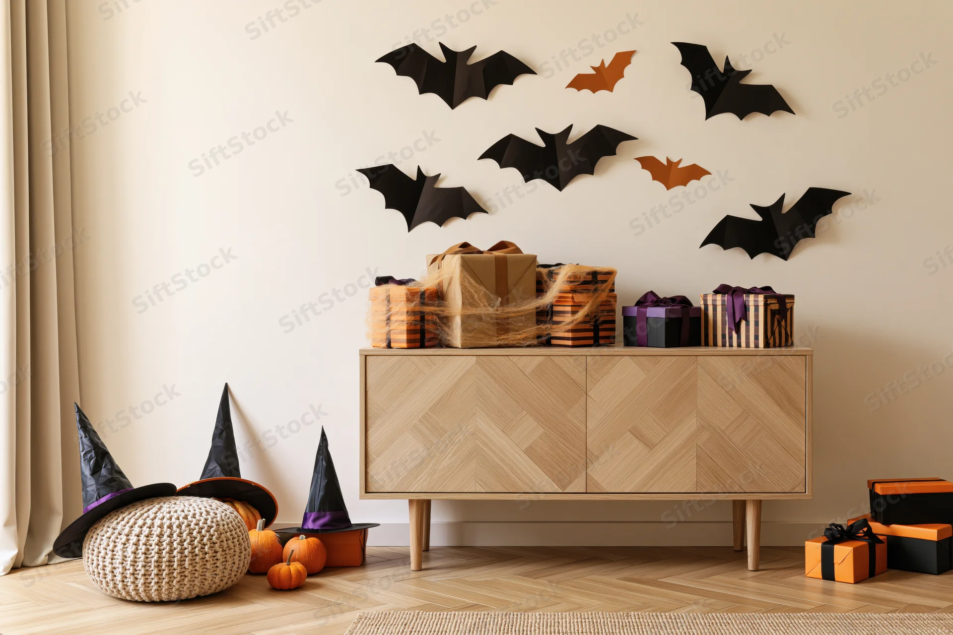 Halloween decorations on a wooden cabinet and wall in a living room corner with pumpkins and witch hats on the floor