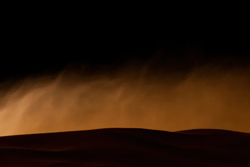 Massive sandstorm haboob rolling over desert dunes at night