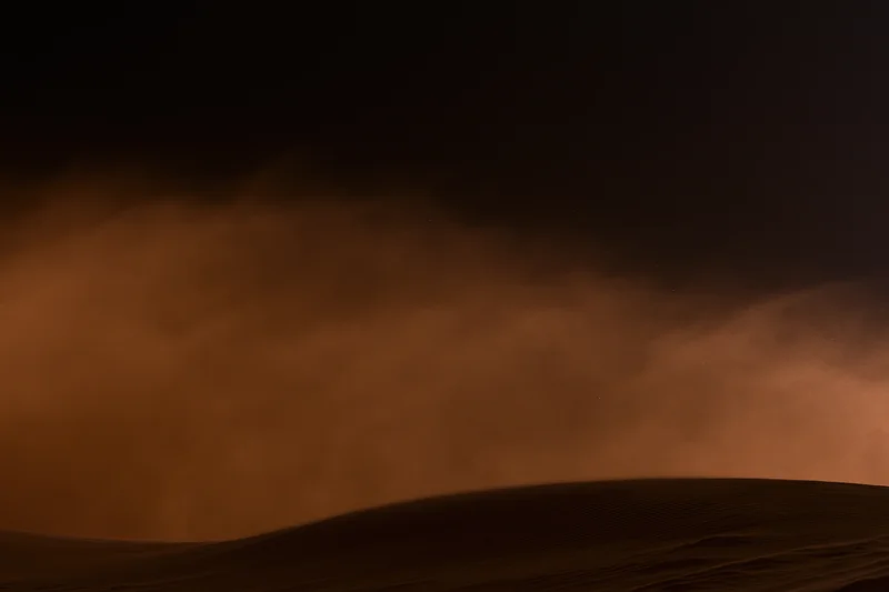 Massive sandstorm haboob rolling across desert dunes at night