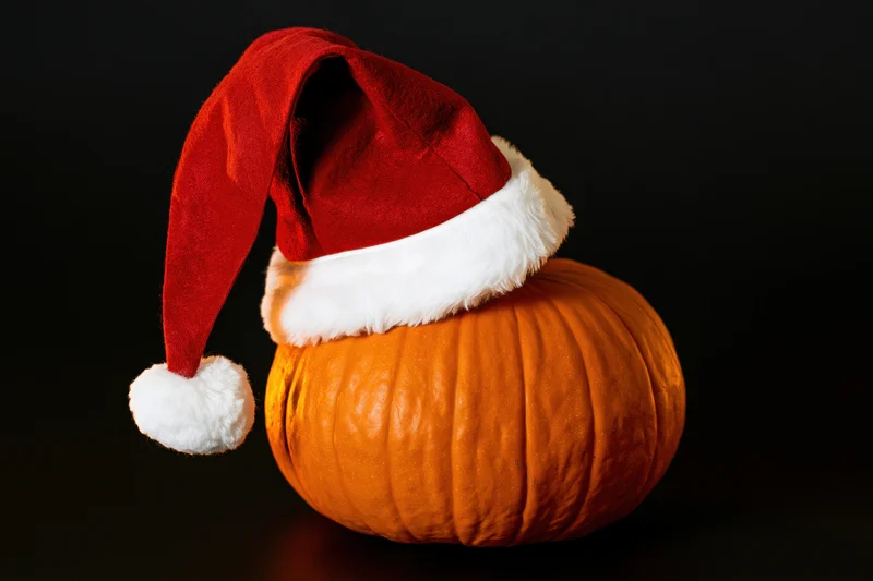 Pumpkin wearing a santa hat on a black background