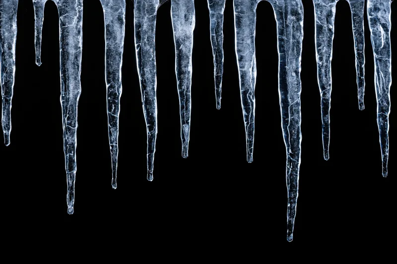 Row of natural icicles hanging down against black background