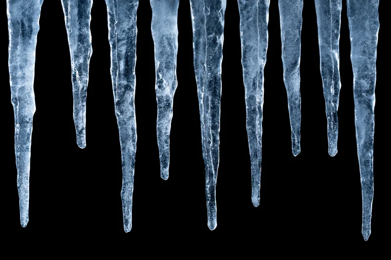 Row of natural icicles hanging vertically against black background