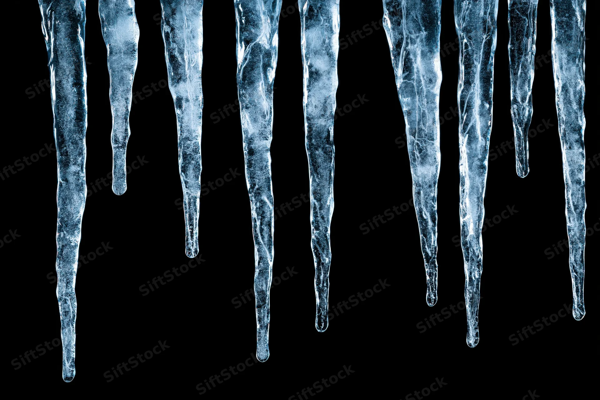 Row of natural icicles hanging vertically against black background