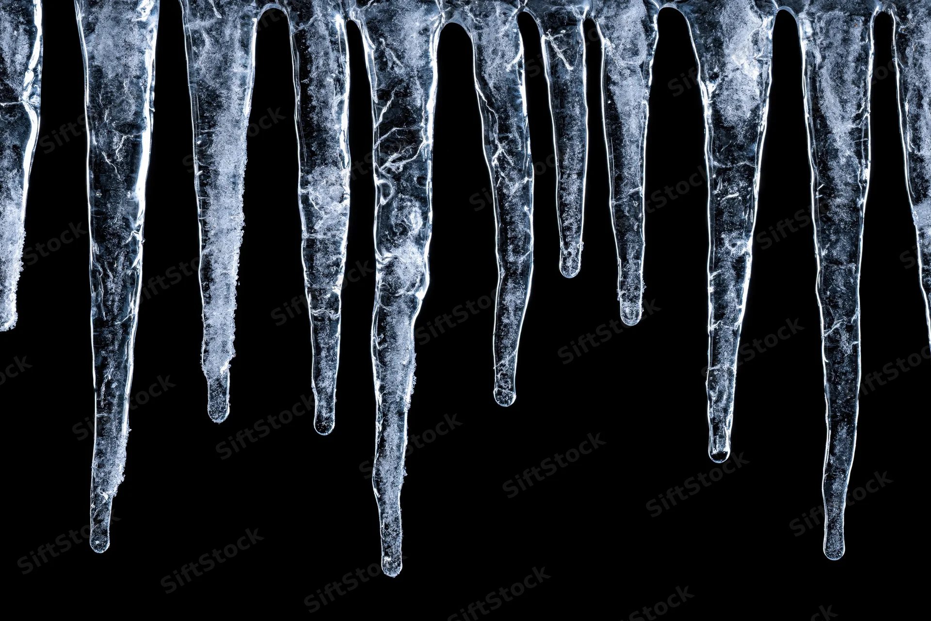 Row of natural icicles hanging down from the top edge against black background