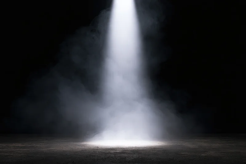 A single spotlight beam cutting through smoke on a dark stage floor