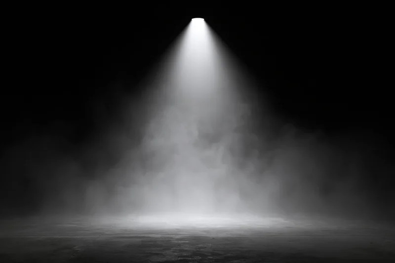 Spotlight beam cutting down through smoke onto empty stage floor