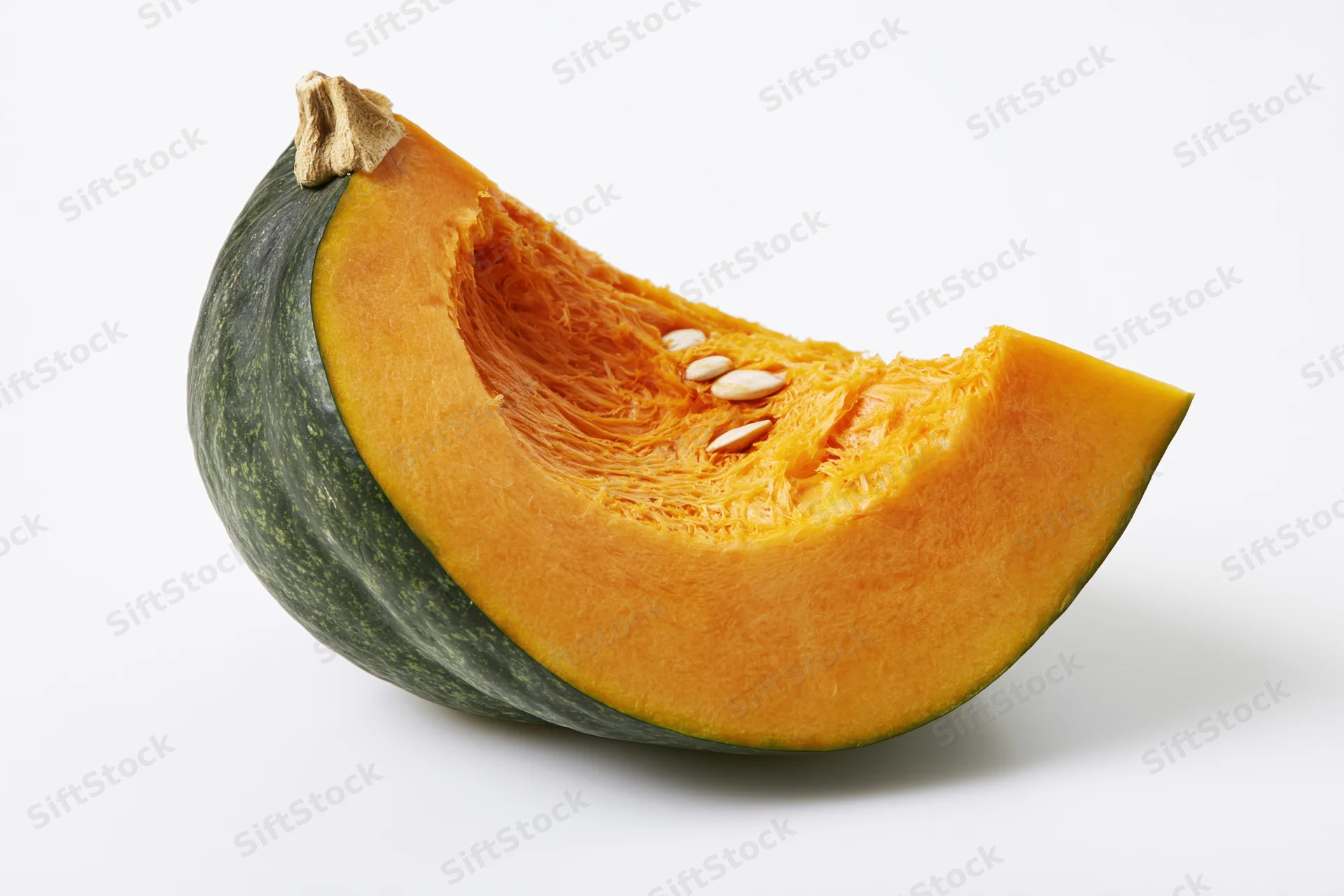 Wedge-shaped slice of kabocha squash cut open showing orange flesh and seeds on white background