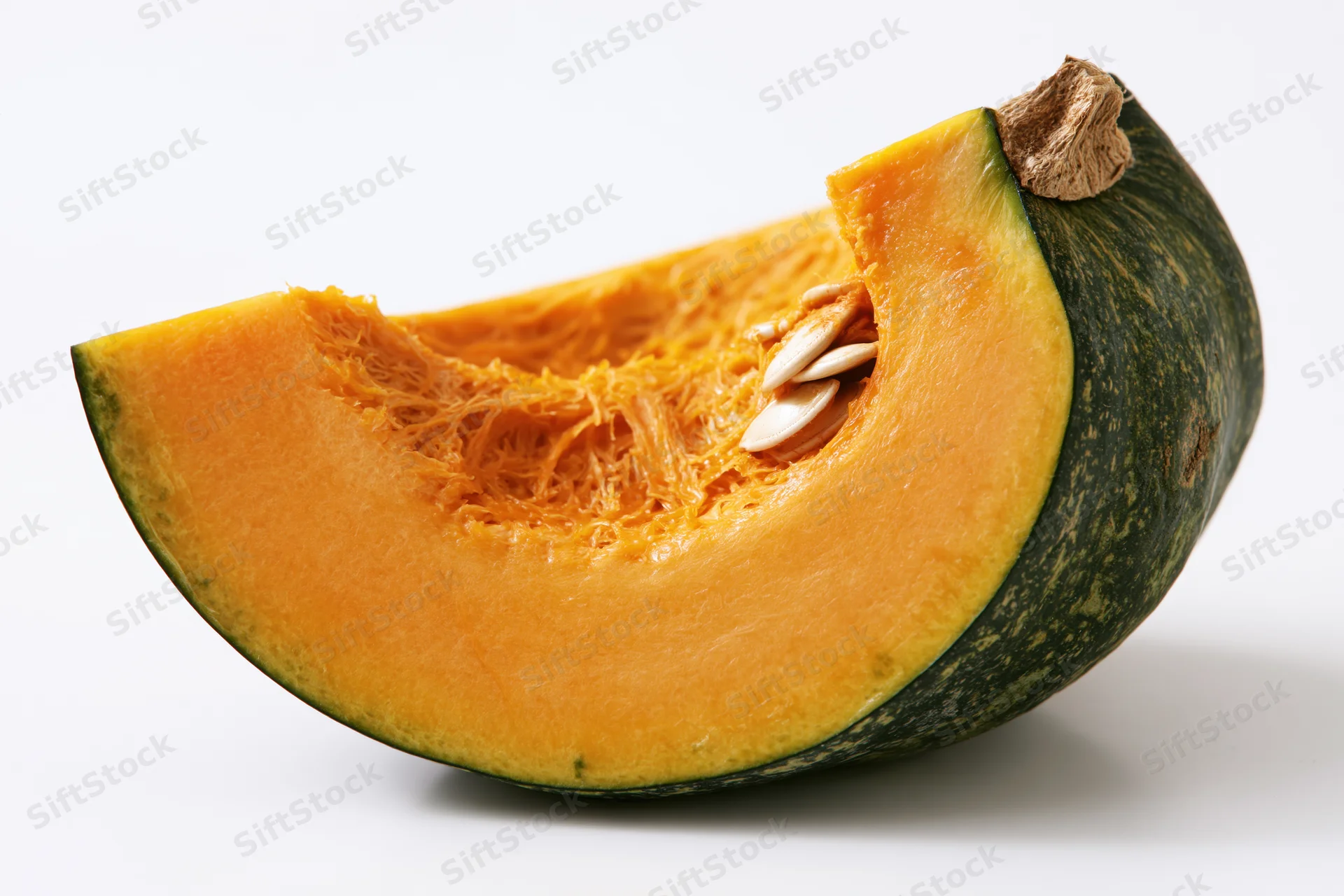 Wedge-shaped slice of kabocha squash cut open showing orange flesh and seeds on white background