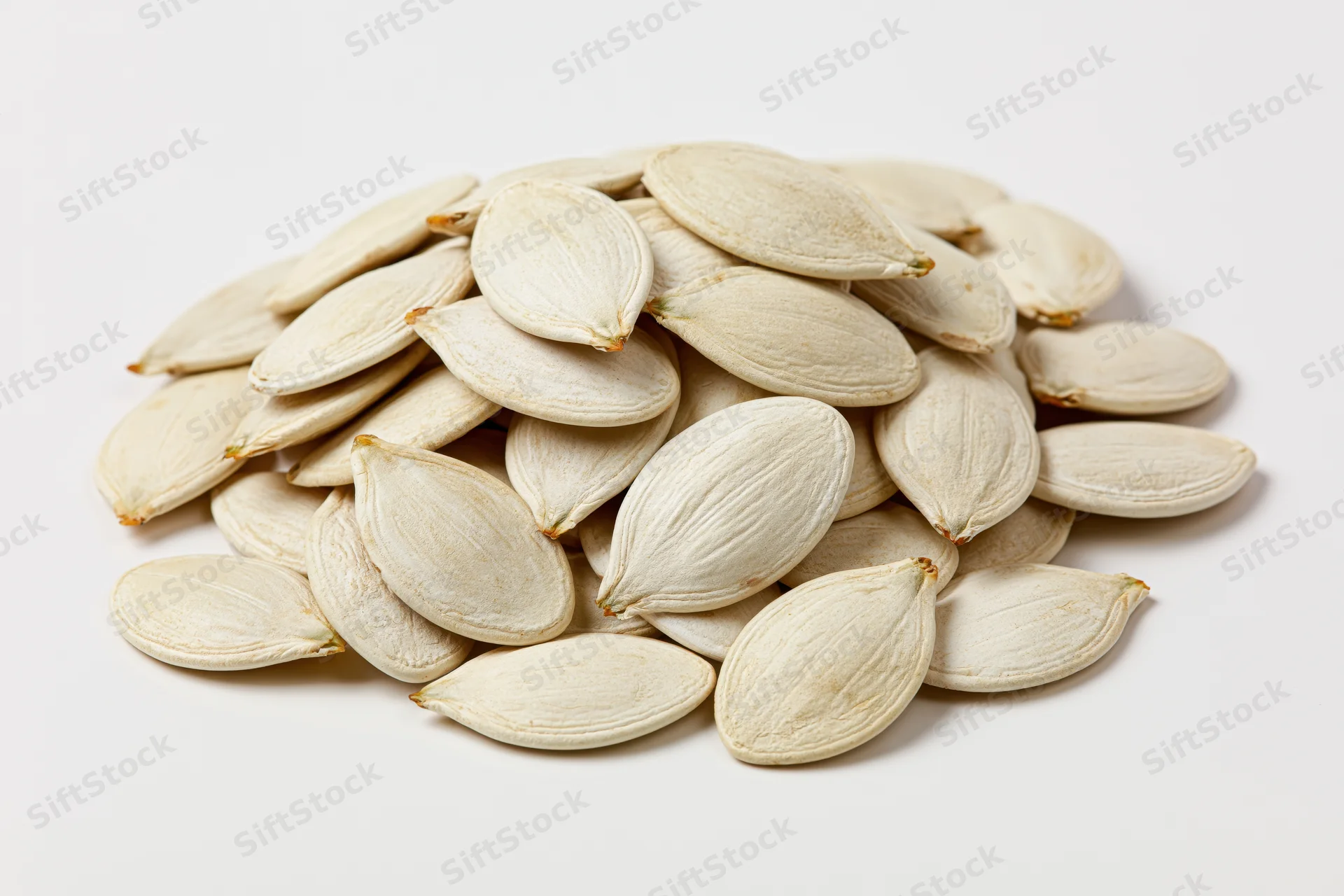 A heap of raw white pumpkin seeds on a plain white surface
