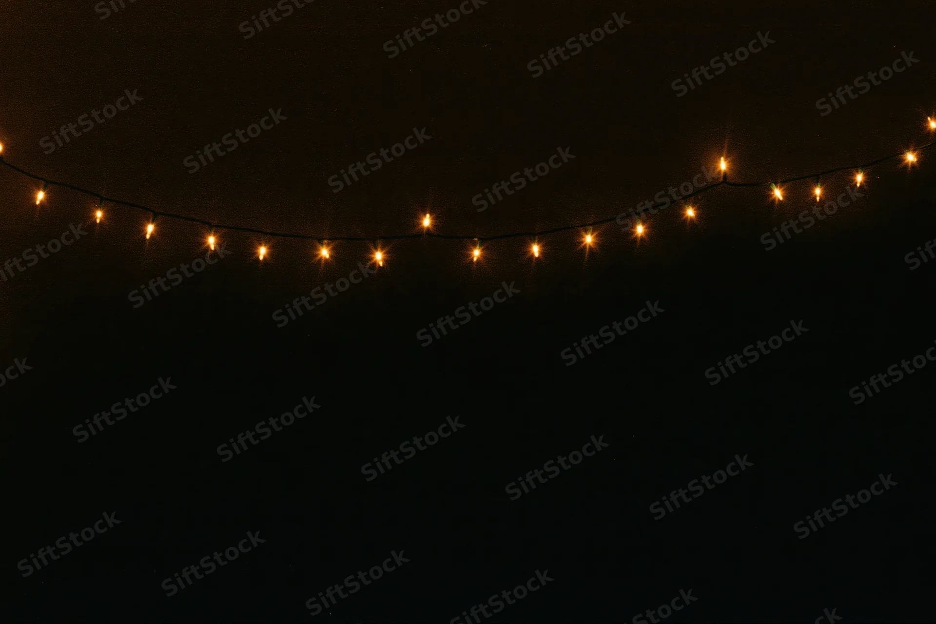 String of warm white fairy lights glowing against dark background with copyspace below