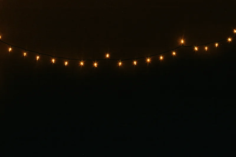 String of warm white fairy lights glowing against dark background with copyspace below
