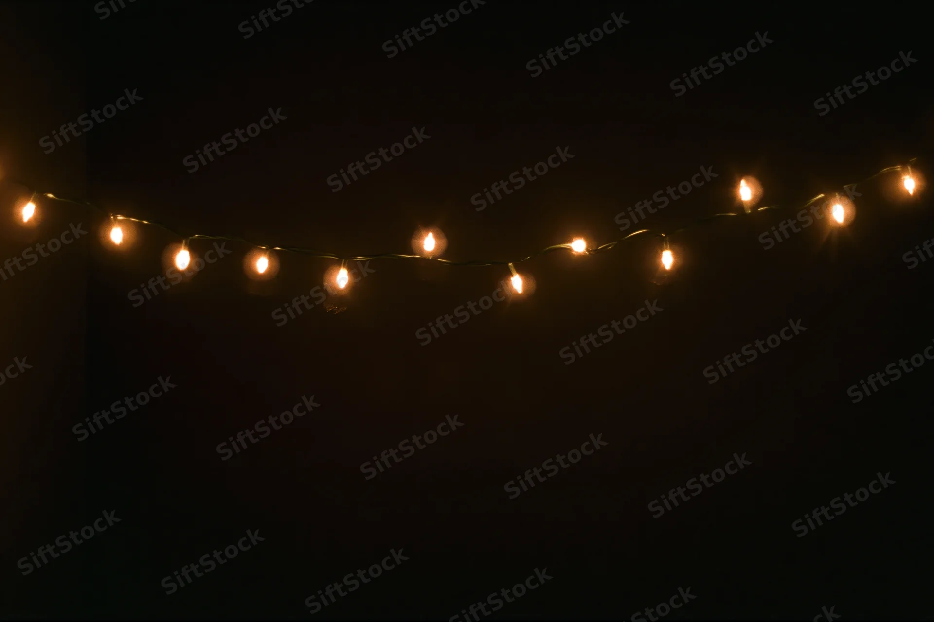 String of warm white fairy lights draped horizontally across dark background
