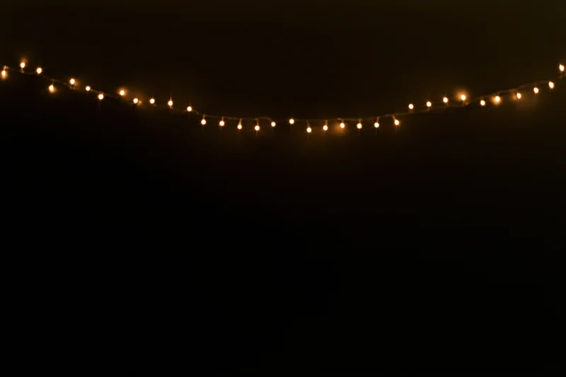 String of warm white fairy lights glowing against dark background with copyspace below
