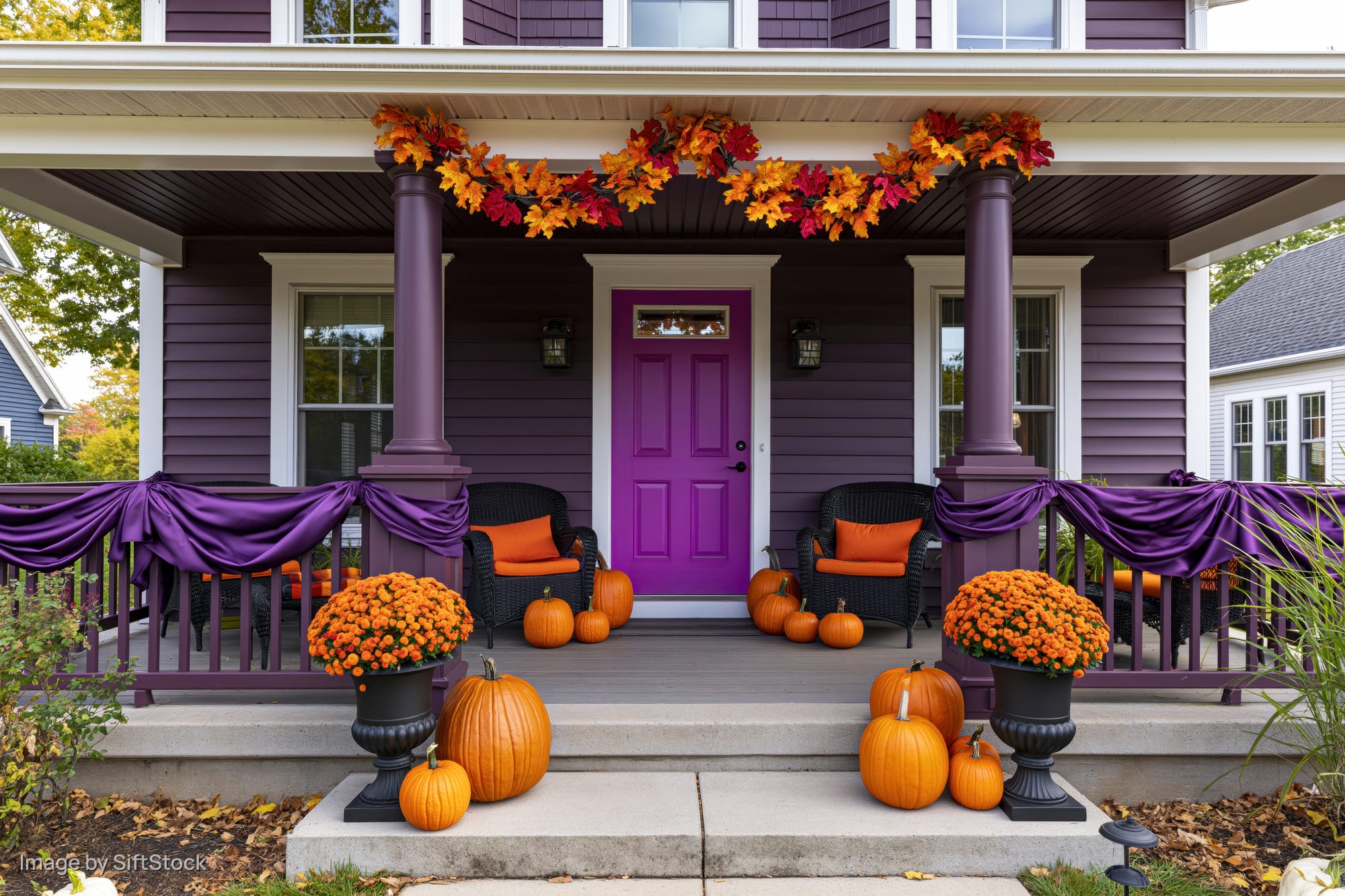 Purple house porch decorated with pumpkins and autumn garland for halloween