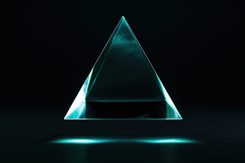 Translucent glass tetrahedron floating above dark surface with teal glow