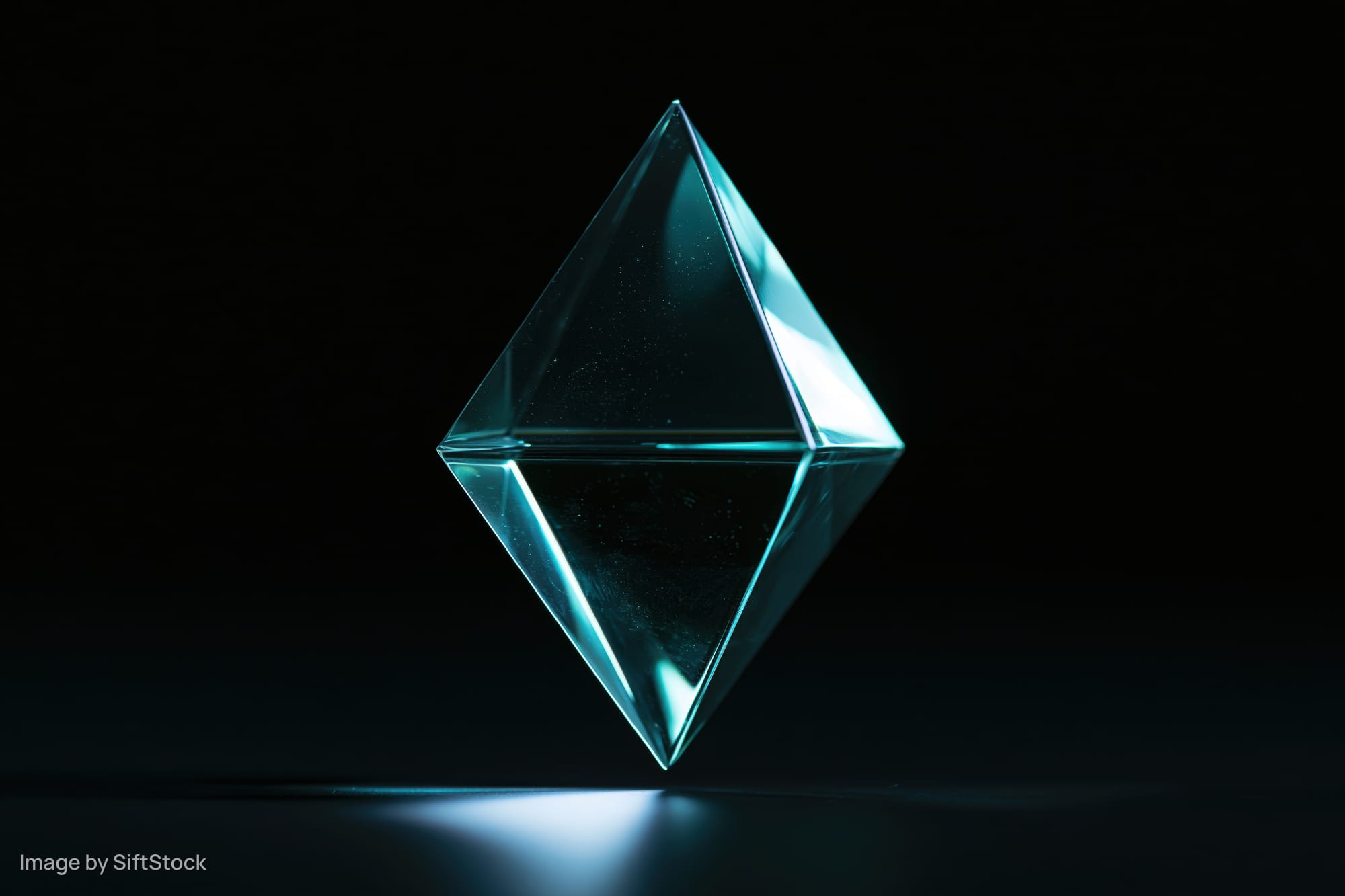 Translucent glass tetrahedron floating against a pure black background