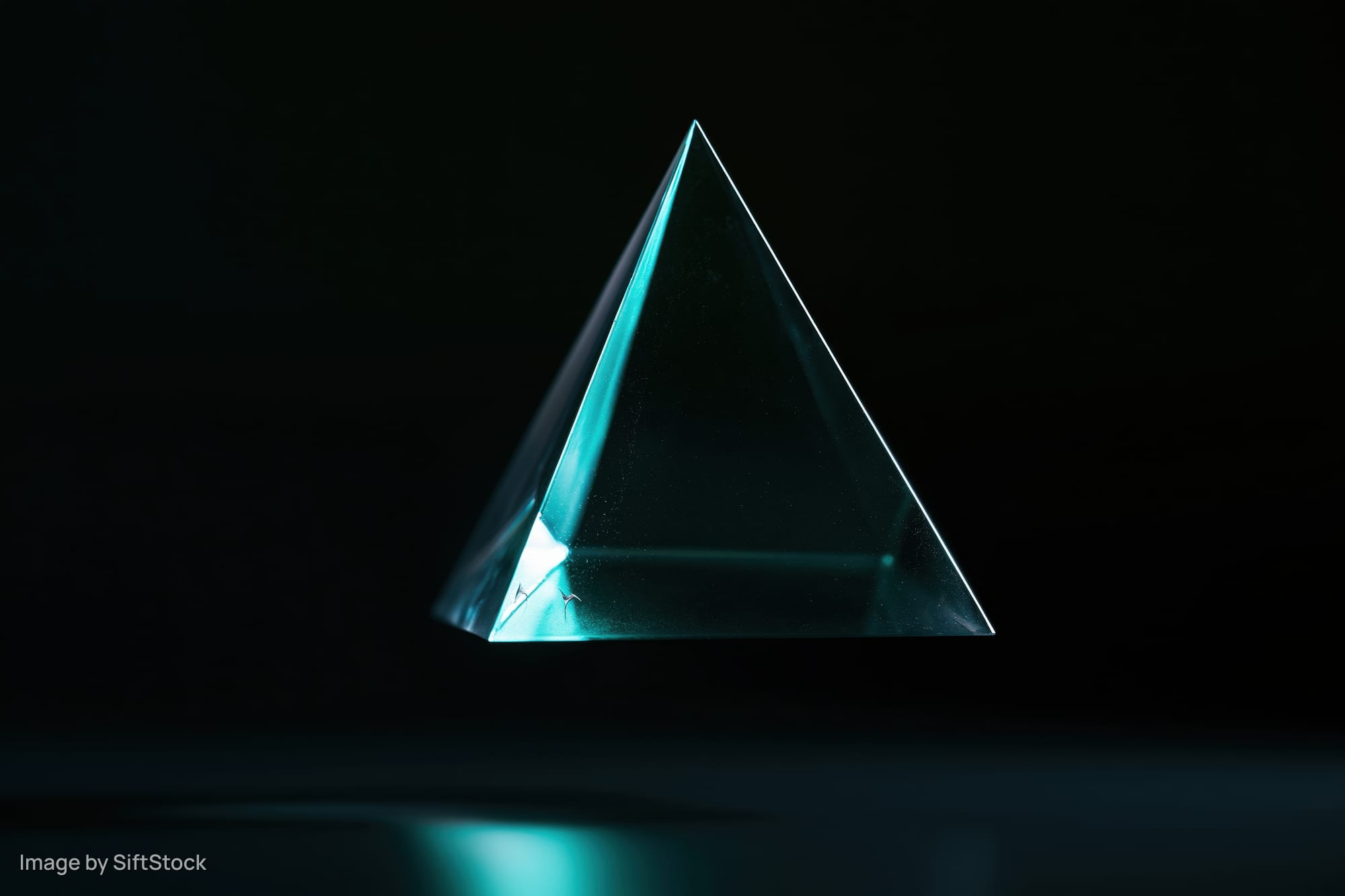 Translucent glass tetrahedron floating against a pure black background