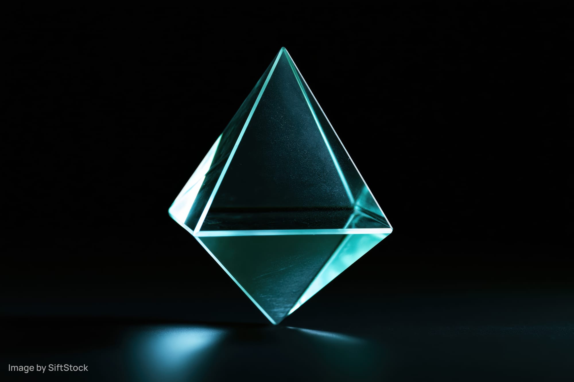 Translucent glass tetrahedron floating against a pure black background