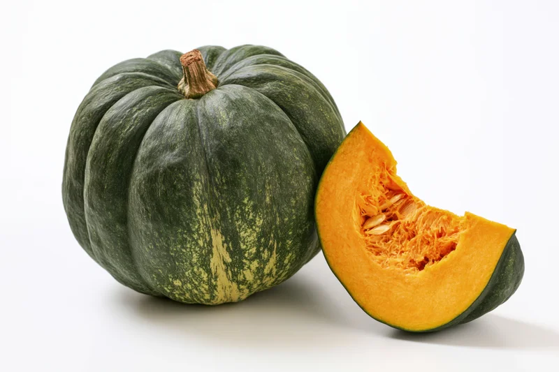 Whole kabocha squash with a cut slice beside it on white background