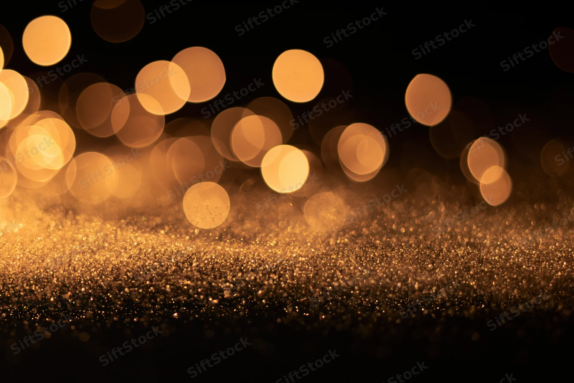 Abstract bokeh lights with golden glitter on dark background