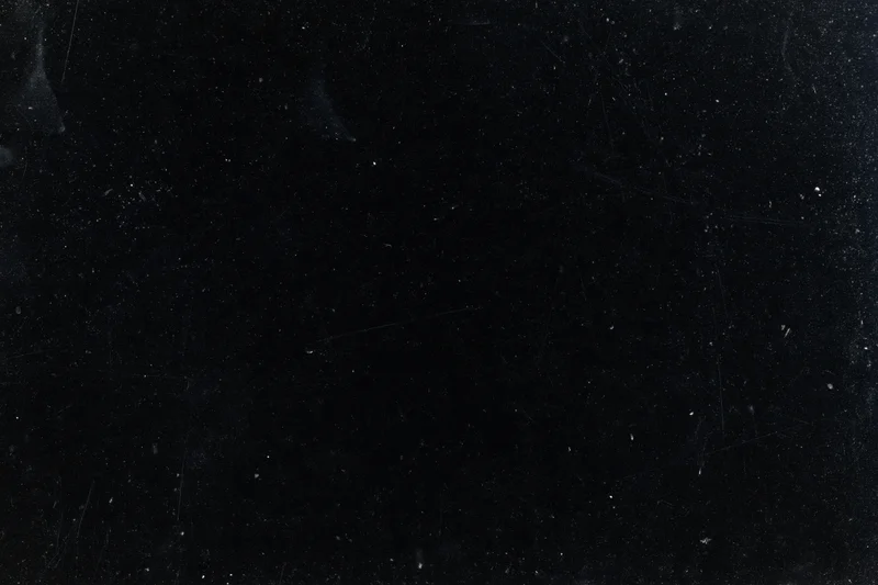 Aged black film negative surface with scattered dust particles and scratches