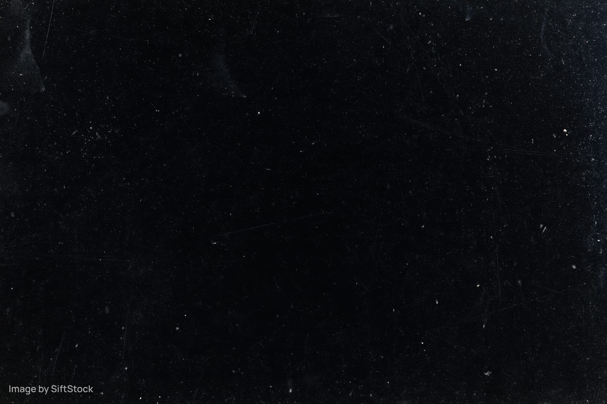 Aged black film negative surface with scattered dust particles and scratches