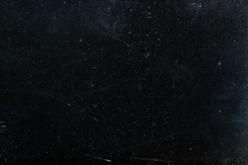 Aged black film negative surface with scattered dust particles and scratches