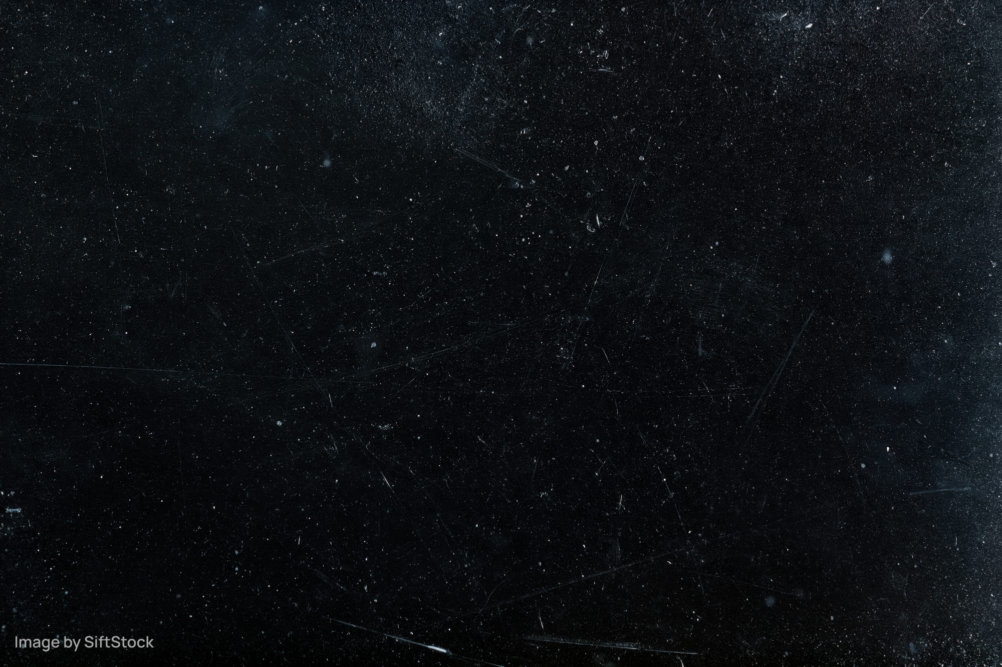 Aged black film negative surface with scattered dust particles and scratches