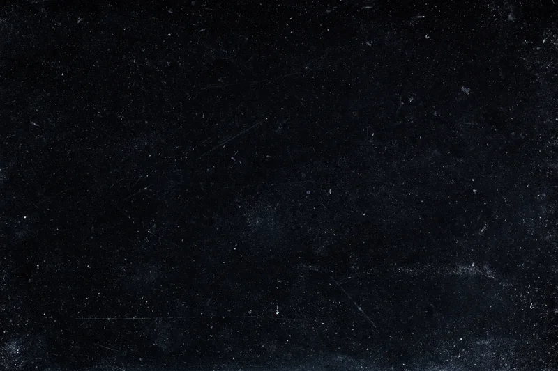 Aged black film negative surface with scattered dust particles and scratches