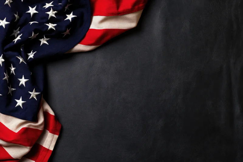 American flag draped in corner on dark leather surface with copyspace
