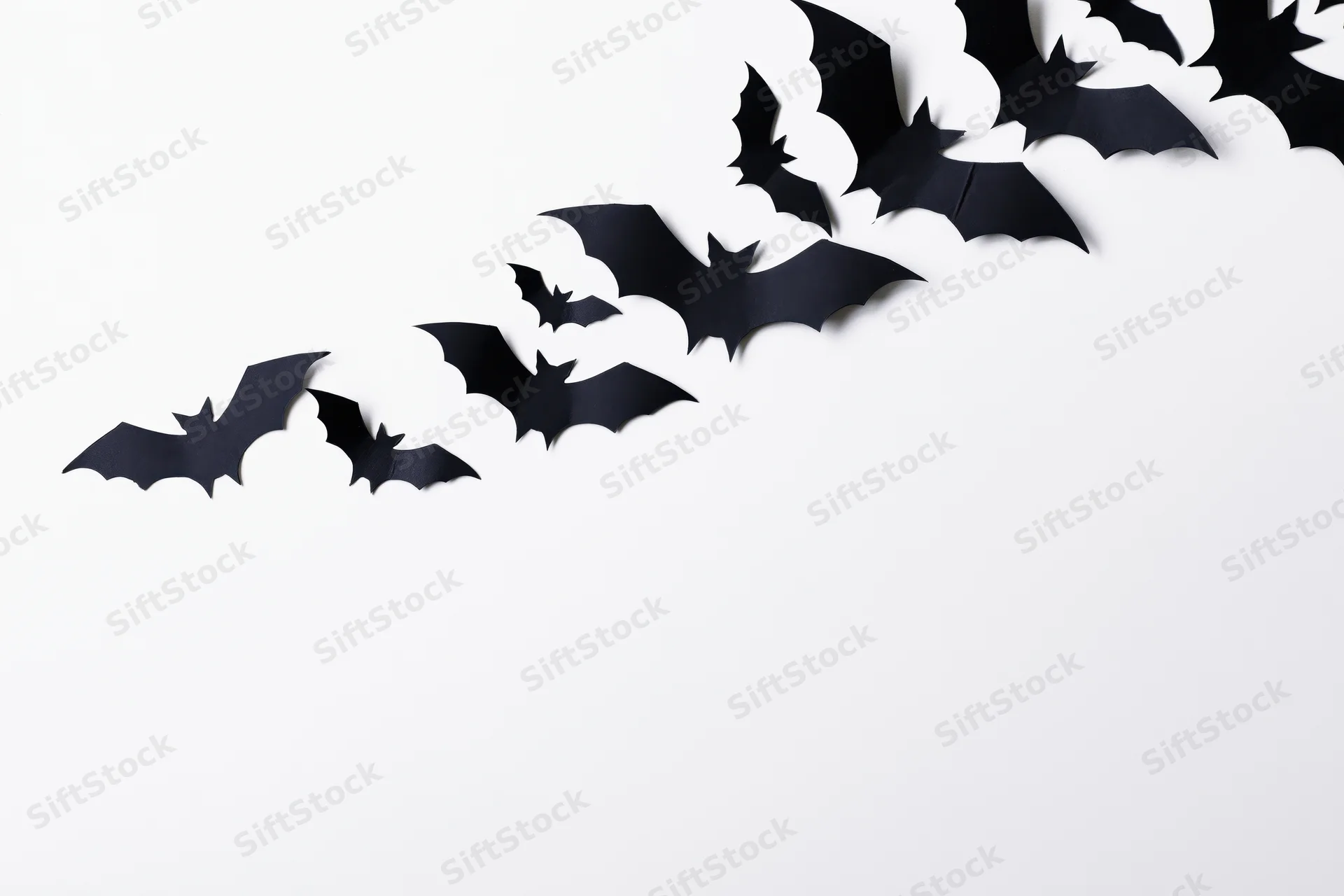 Black paper bat cutouts arranged diagonally across a white background