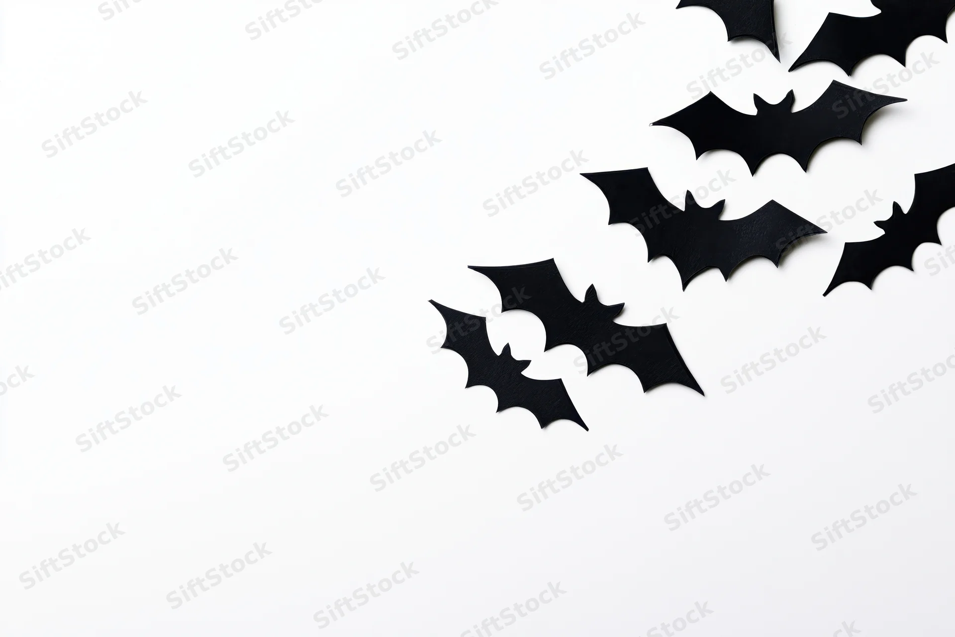 Black paper bat cutouts arranged diagonally on white background