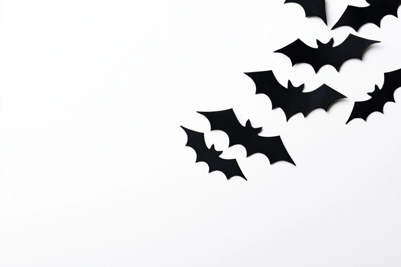 Black paper bat cutouts arranged diagonally on white background