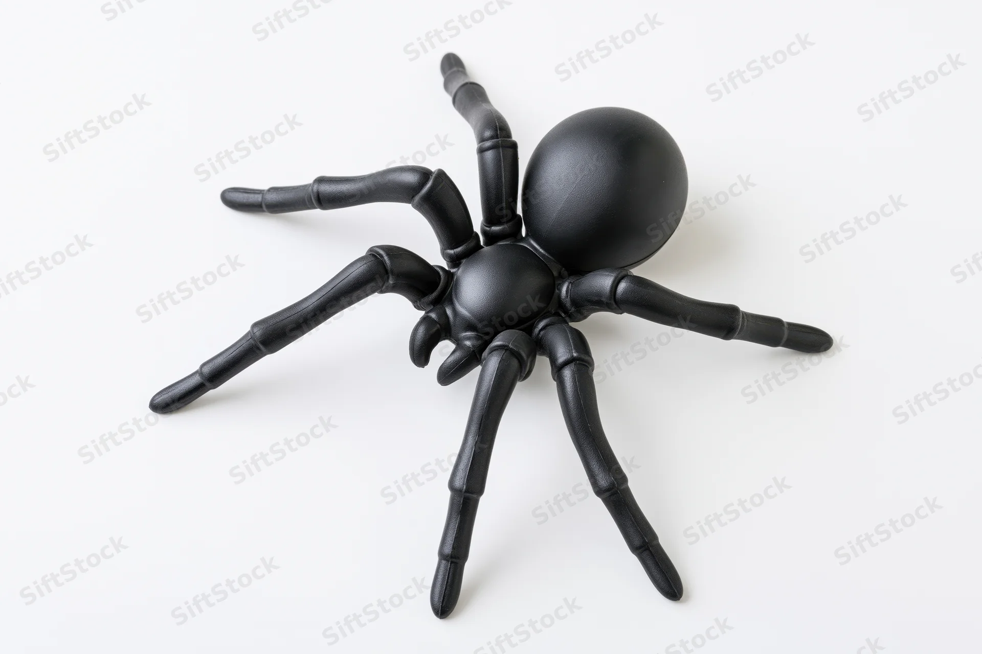 Black plastic toy spider figurine isolated on white background
