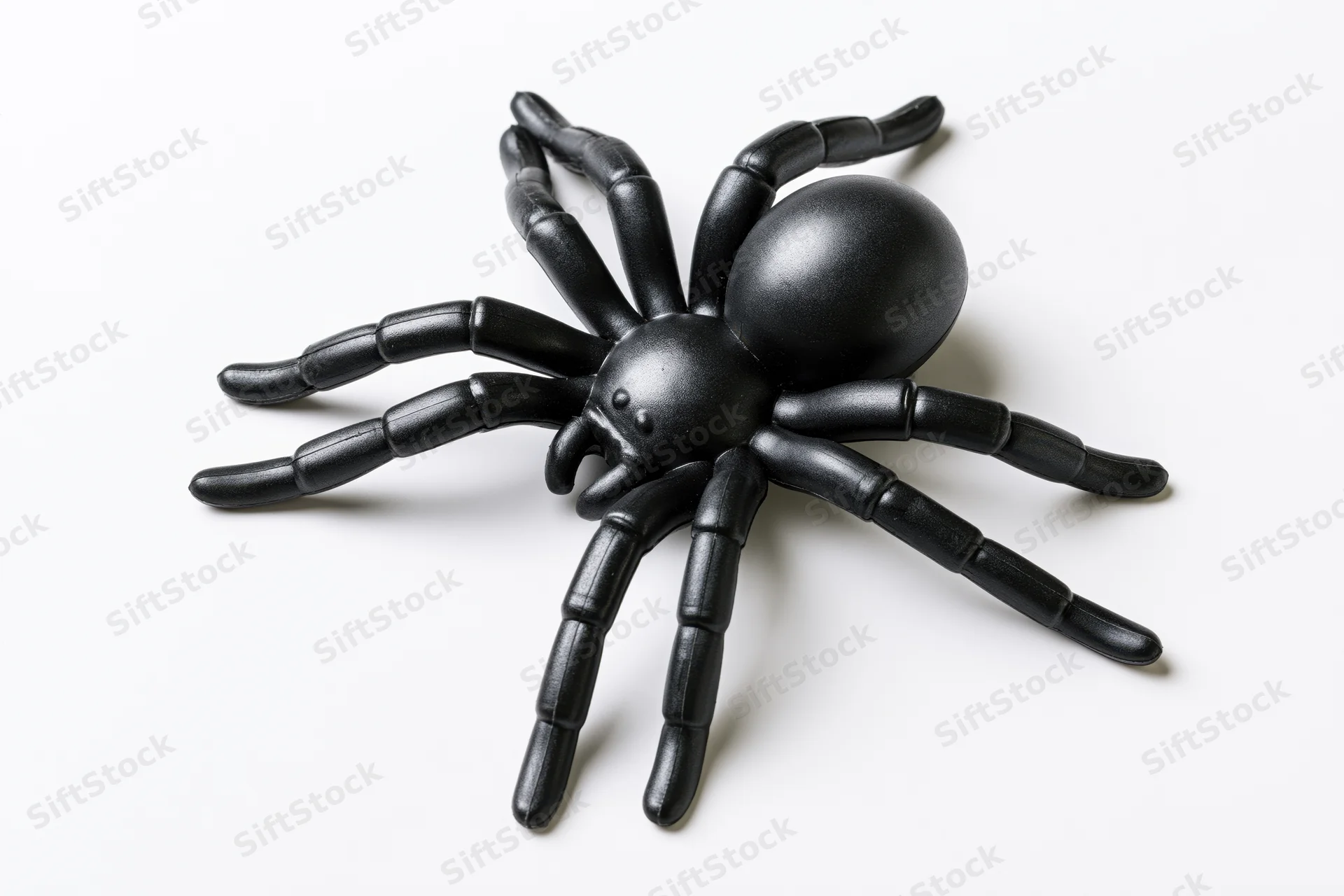 Black plastic toy spider figurine isolated on white background