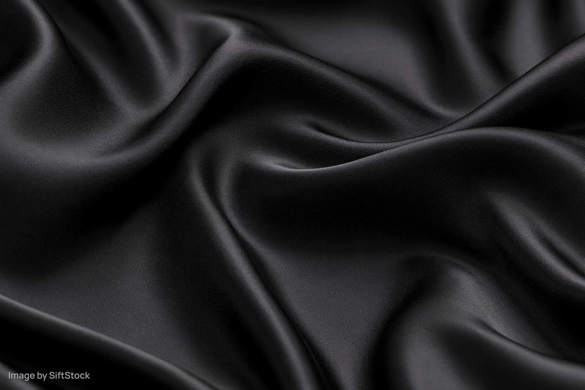 Black silk fabric draped in flowing folds filling the frame