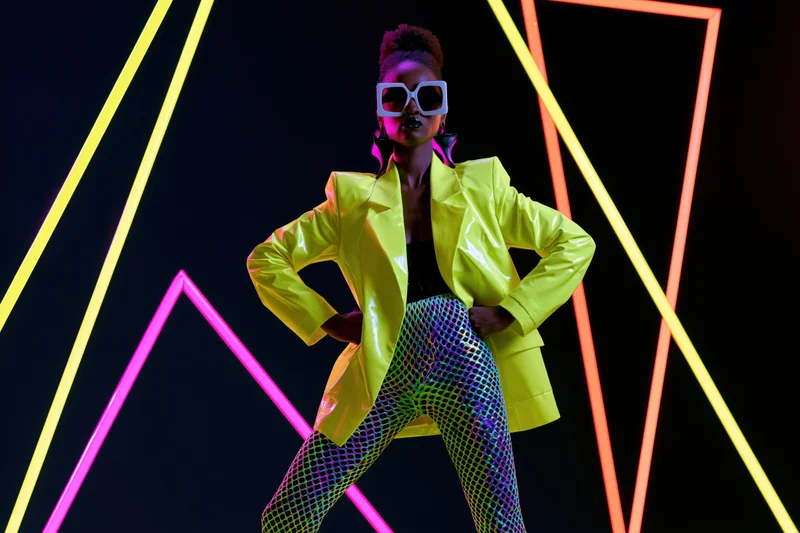 Black woman in power pose wearing neon yellow jacket and mesh leggings against glowing geometric lights