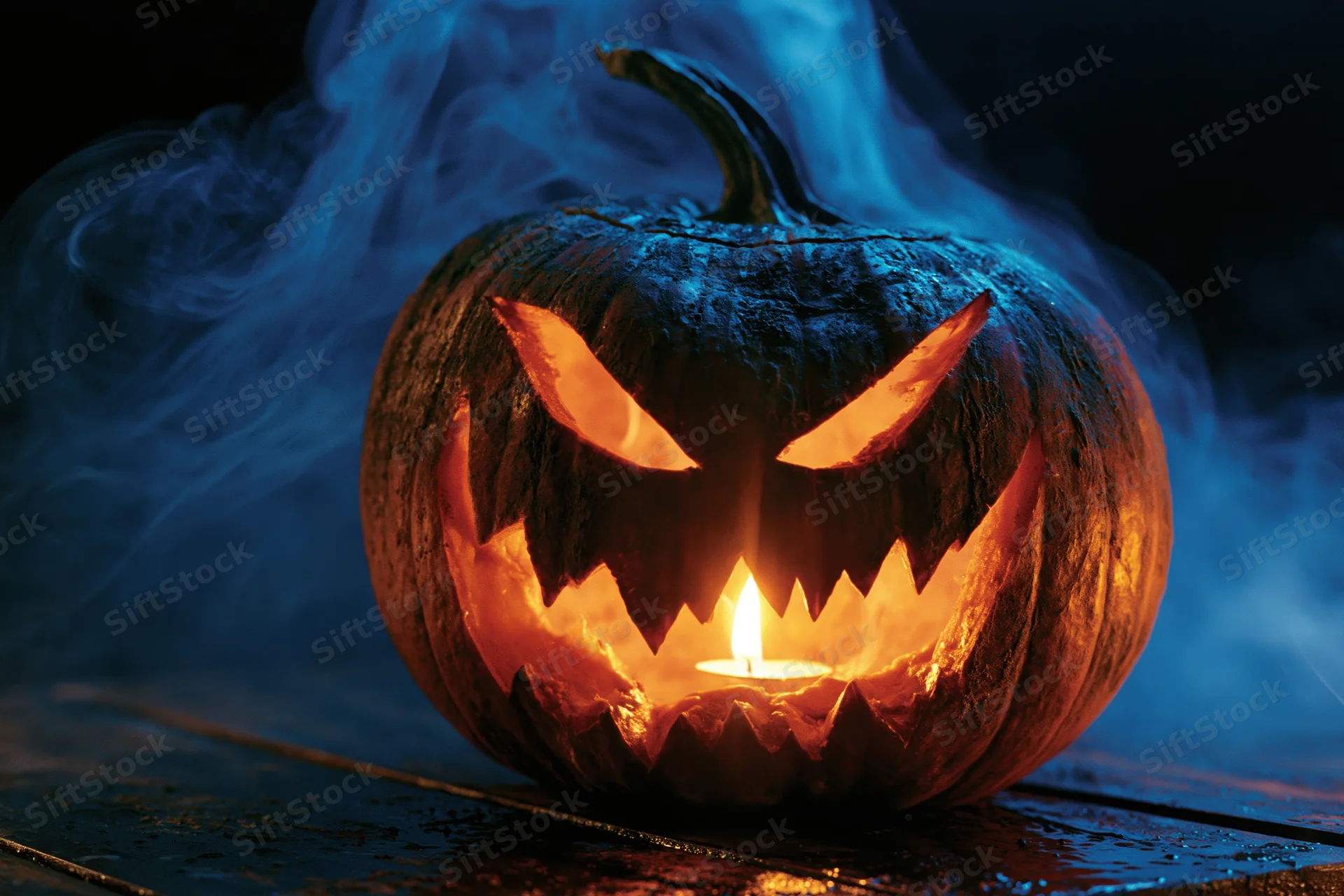 Carved jack-o-lantern glowing with candlelight on wooden surface surrounded by blue smoke at night