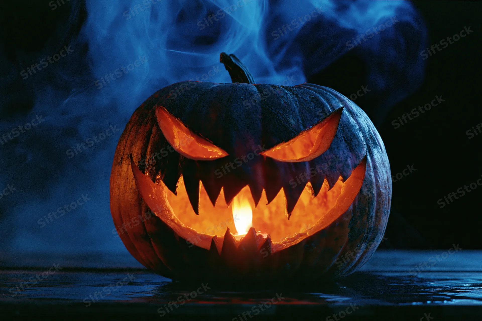 Carved pumpkin with glowing face and blue smoke on dark surface