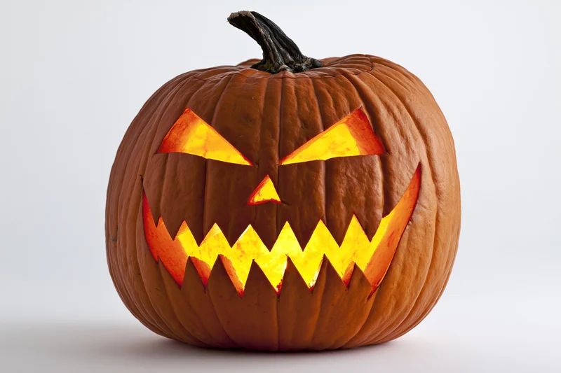 Carved pumpkin with jagged glowing grin on white background