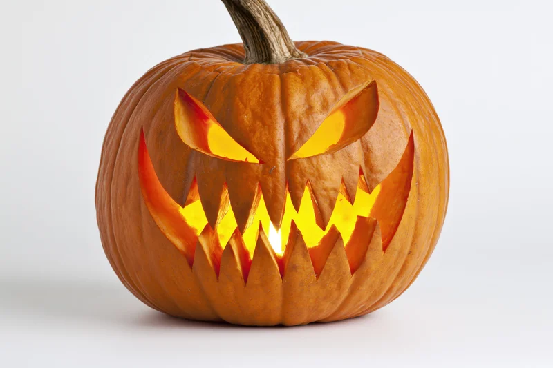 Carved pumpkin with jagged glowing face on white background