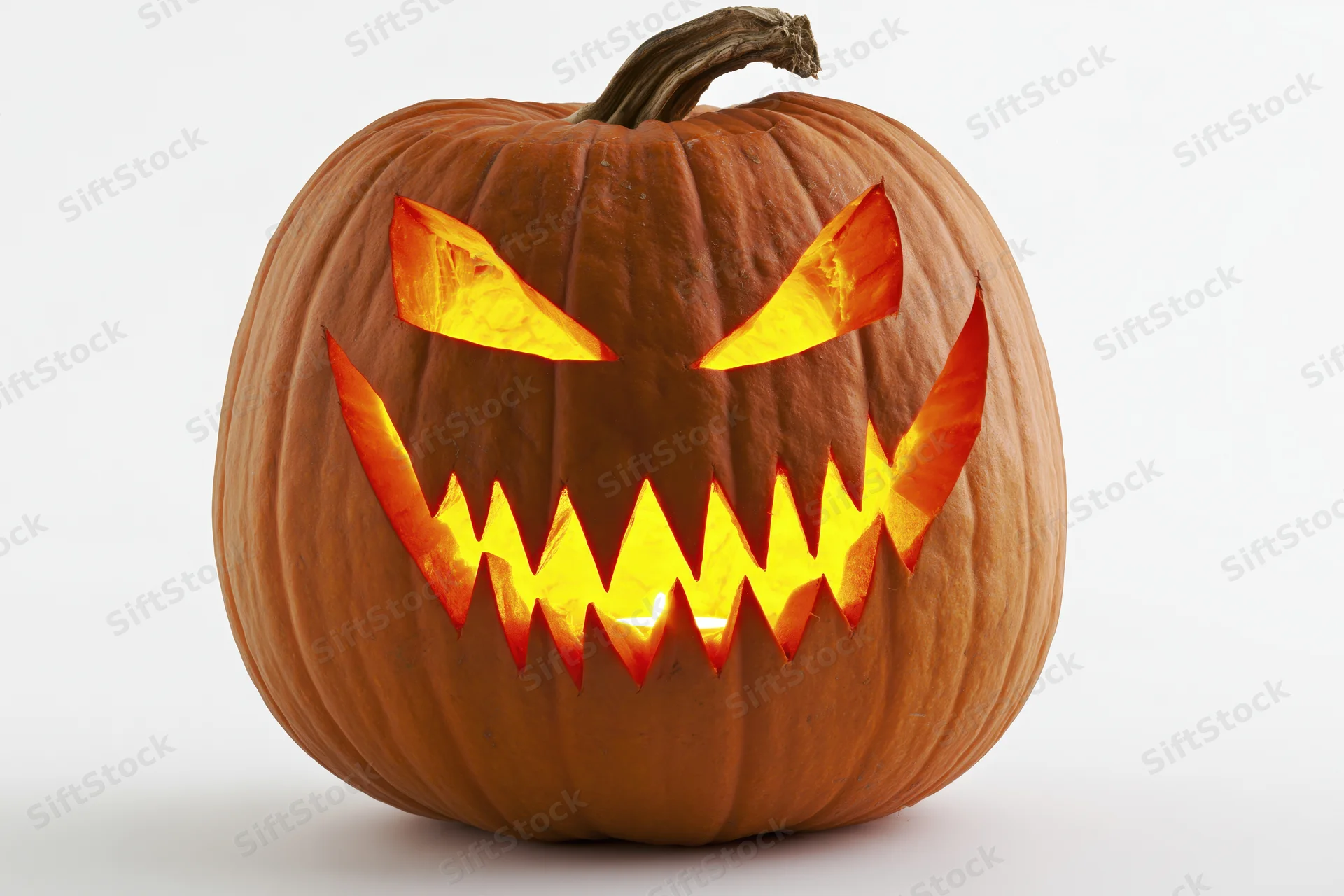 Carved pumpkin with jagged glowing face on white background