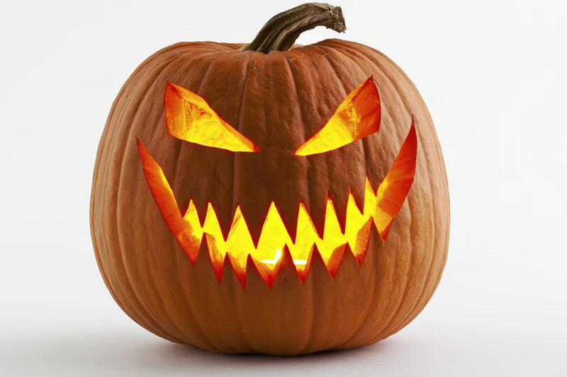 Carved pumpkin with jagged glowing face on white background
