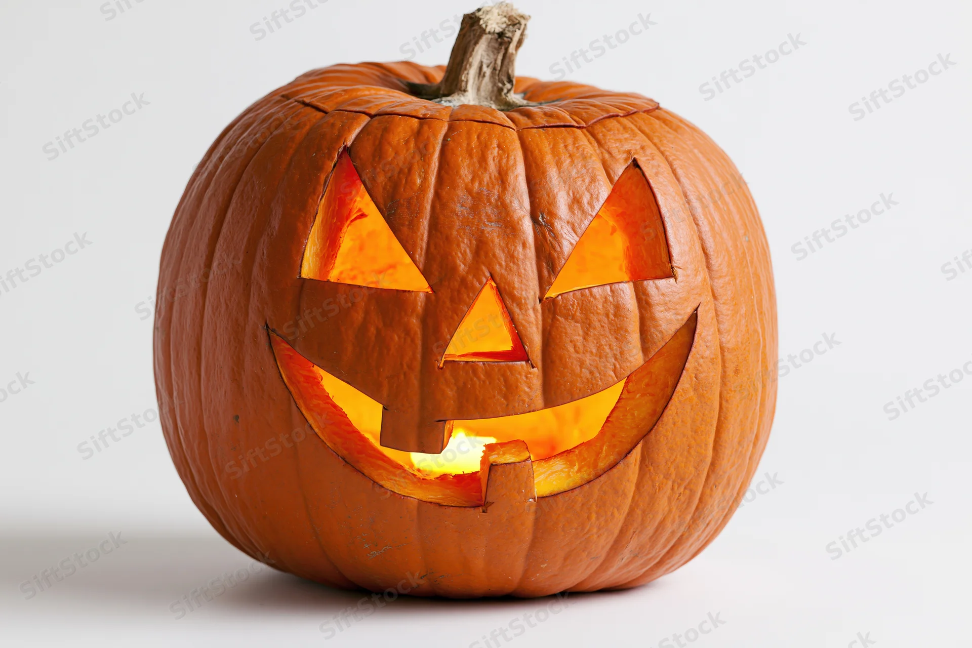Carved pumpkin with glowing grinning face on white background