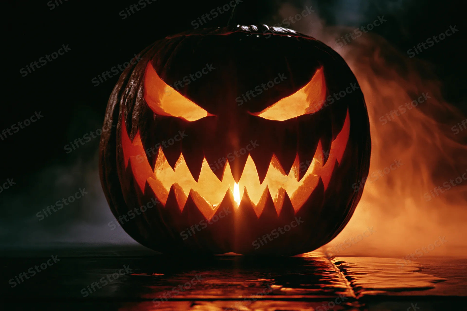 Carved pumpkin with jagged grin glowing in dark smoke-filled setting