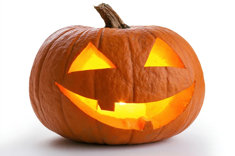 Carved pumpkin with glowing triangular eyes and wide smile on white background