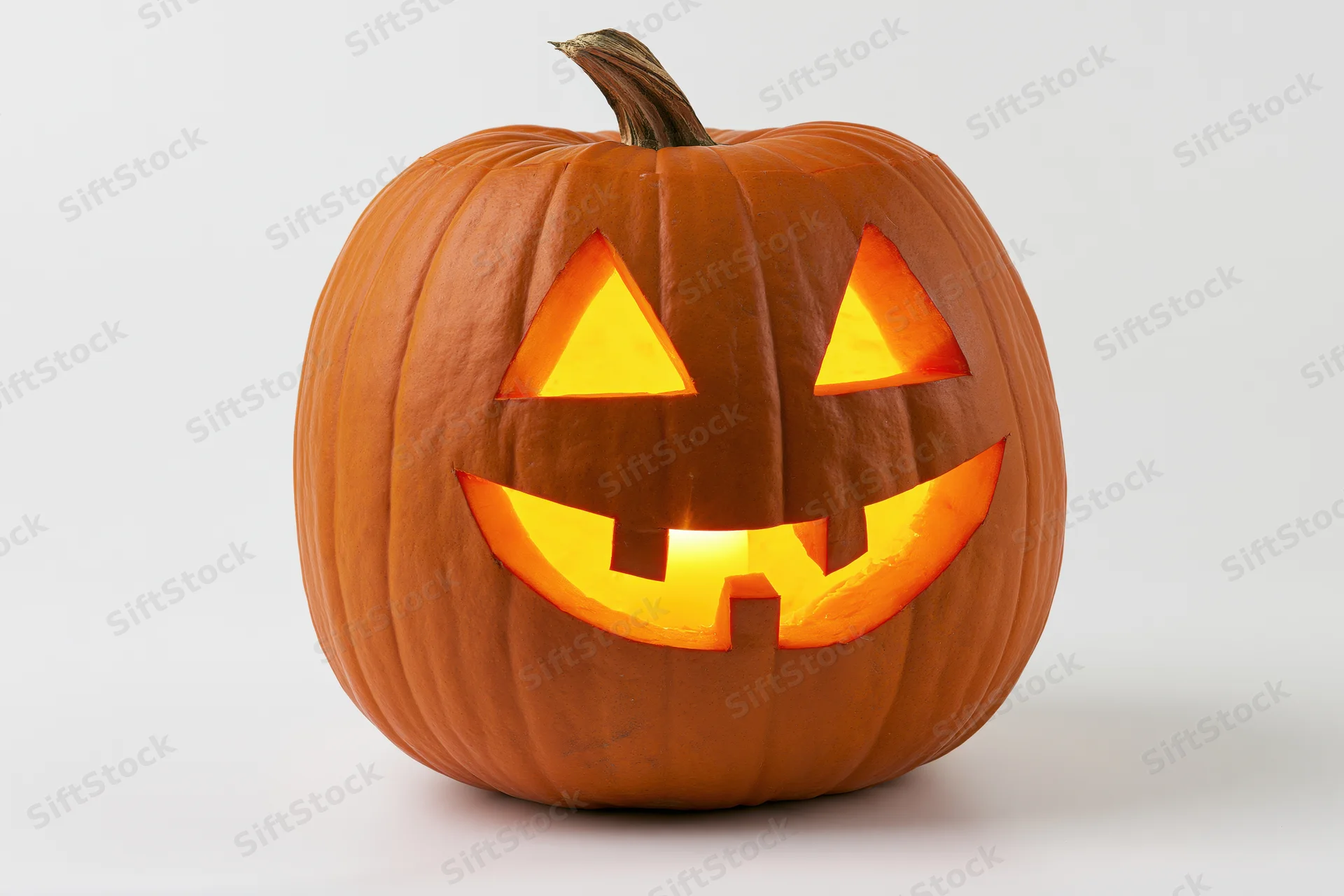 Carved pumpkin with glowing triangular eyes and smiling mouth on white background