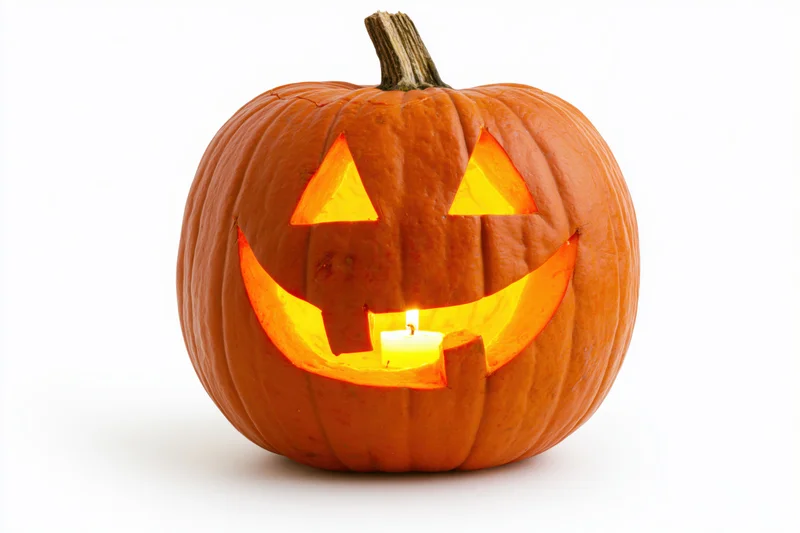 Carved pumpkin with triangular eyes and smiling mouth lit by candle on white background